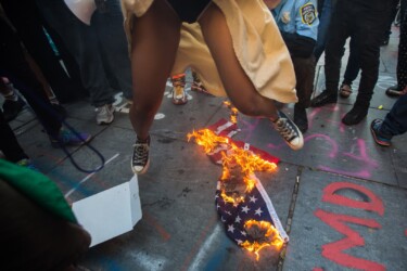 Independence Day. New YorkCity residents continue on thestreets raising their voicesagainst racism and calling forjustice. Woman jumps overburning USA flag. 2020